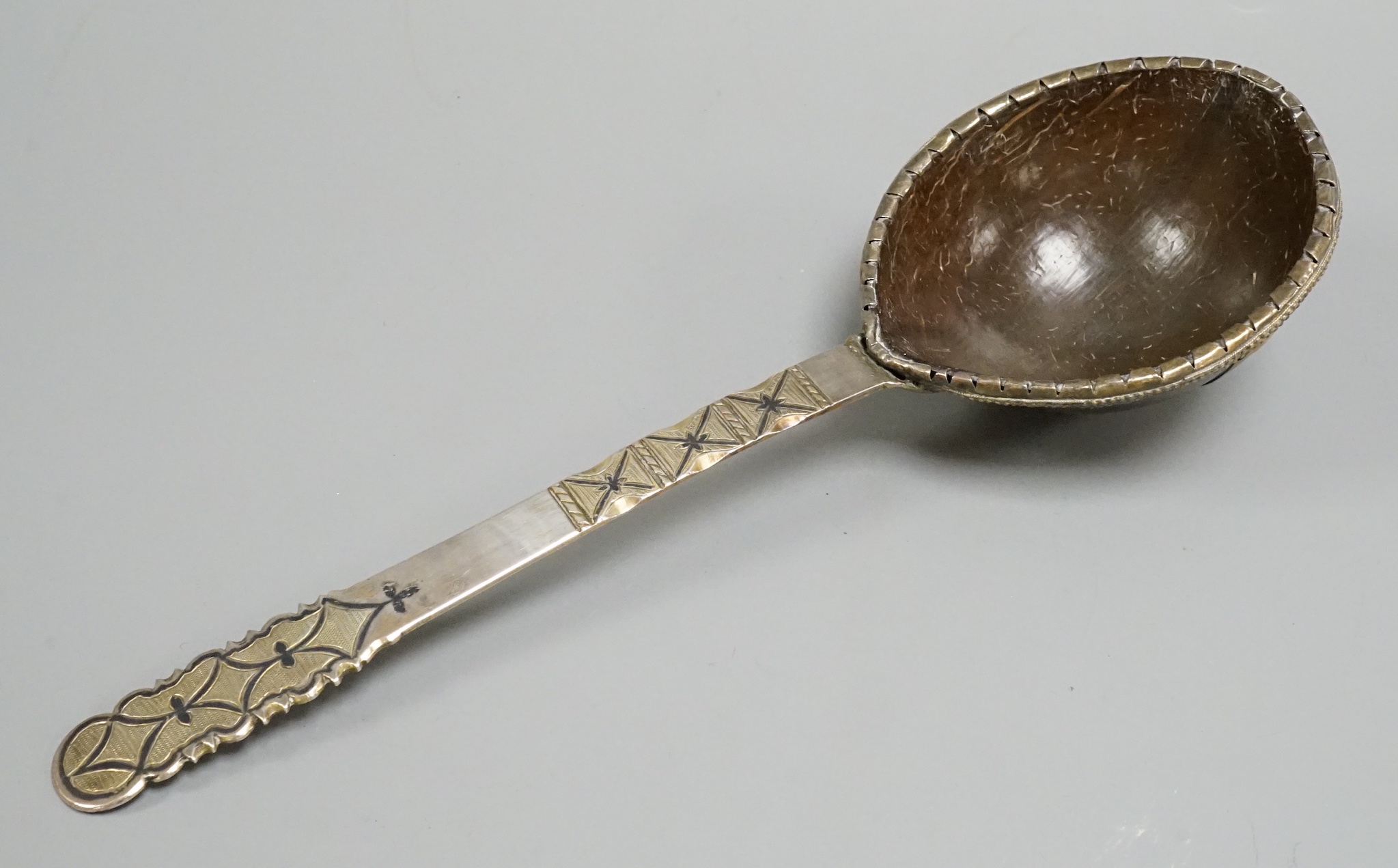 An 18th Russian white and parcel gilt metal ladle, the handle with a niello inlay and a coconut bowl. 28.5cms.